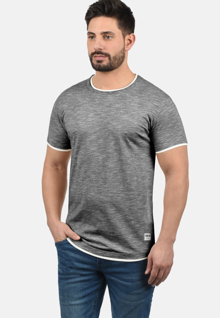 Grå T-skjorte med kort erm, textured stoff, hvit rundhals og ermer, samt en liten etikett nederst til venstre.