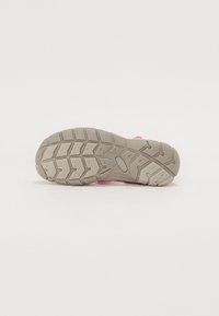 Pink athletic shoe with a textured, rubber sole featuring a tread pattern for grip, and lightweight synthetic upper with adjustable straps.