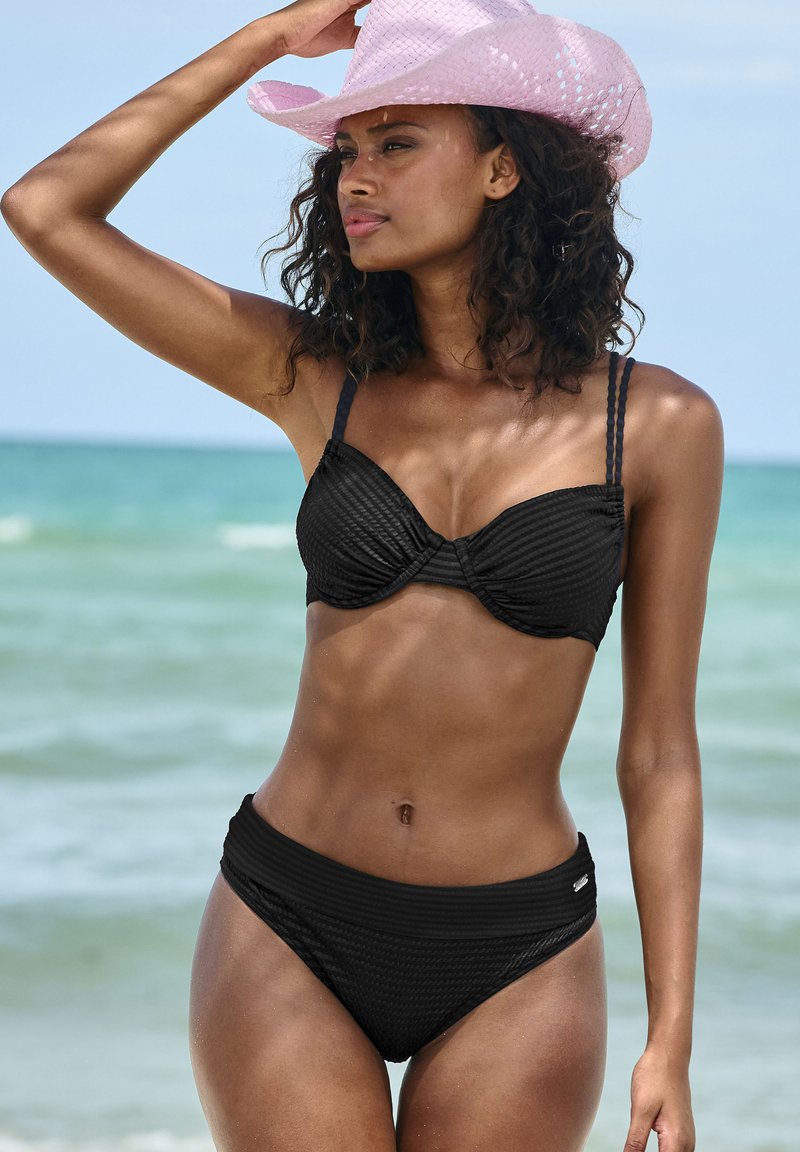 Set bikini nero con tessuto testurizzato; il top bandeau presenta un design plissettato, spalline regolabili e slip a vita alta per una maggiore copertura.