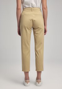 Pantaloni khaki con vestibilità tailored, gamba dritta, due tasche posteriori e una texture morbida, abbinati a sneakers bianche.