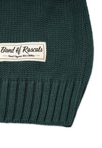 Stickad grön mössa med ribbad textur. Har en rektangulär krämfärgad etikett med svart text: "Band of Rascals" och "Finest Organic Kids Clothes."