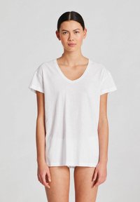 Tricou alb cu decolteu în V, realizat dintr-un material moale, având mâneci scurte și o croială lejeră. Textură netedă, fără modele sau accente.