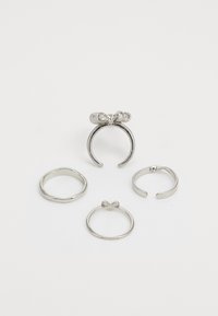 Juego de cuatro anillos de plata con un llamativo diseño en forma de lazo, acabados lisos y texturizados, con formas variadas: bandas abiertas y cerradas.