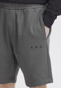 Grå bomuldsshorts med elastisk talje, sidelommer og et trykt "A.R.C." logo på venstre ben. Glat tekstur og knælangt design.