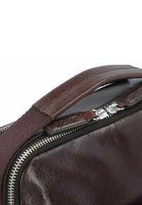 Borsa in pelle marrone con superficie liscia, dotata di chiusura con zip, maniglia in tessuto e zip in metallo.