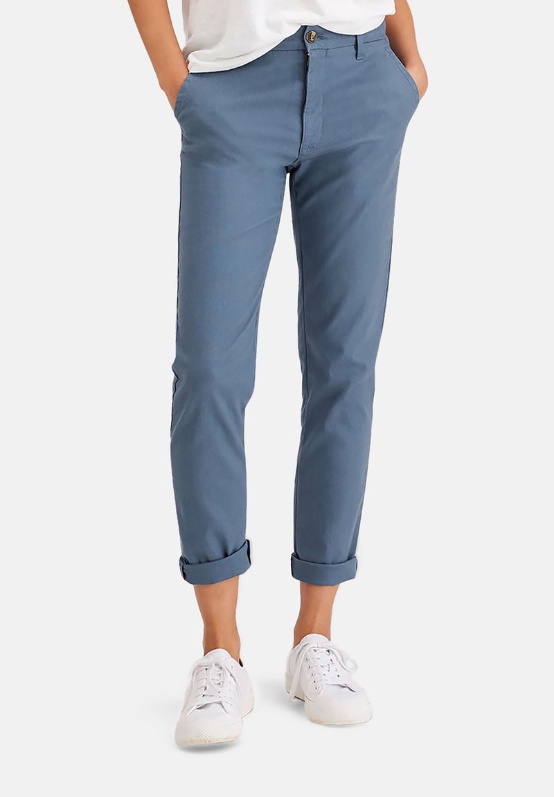 Blå bomullsbyxor med rak passform, uppvikta cuffs och framfickor, matchade med vita sneakers. Enkel knapp- och dragkedjestängning.