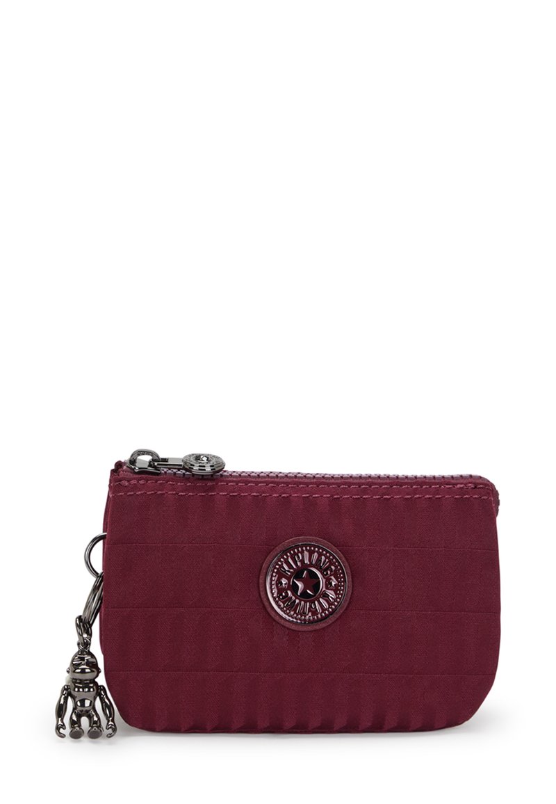 Burgundy tygplånbok med strukturerade ränder, dragkedjestängning, cirkulär logotypdetalj och metallberlocker i form av en leksaksgubbe.