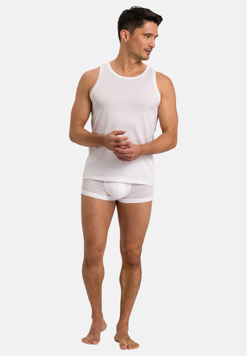 Weißes Tanktop und durchsichtige weiße Unterwäsche, beide aus glattem Material gefertigt. Das Tanktop hat einen Rundhalsausschnitt und eine taillierte Silhouette.