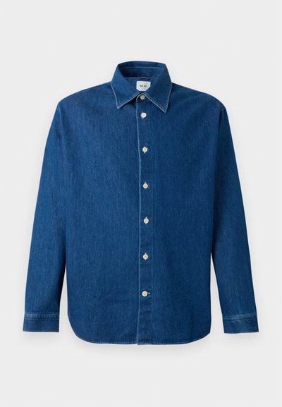 Chemise en denim bleu à manches longues avec fermeture à boutons sur le devant et col traditionnel, présentée sur un fond blanc uni.