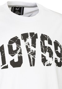 Weißes Baumwoll-T-Shirt mit großem, schwarzem, rissigem Druck "1969" auf der Vorderseite. Rundhalsausschnitt mit grauem Innenschild.