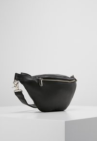 Borsa nera in pelle con forma curva, chiusura con zip e tracolla regolabile. Presenta hardware argentato e una superficie testurizzata.