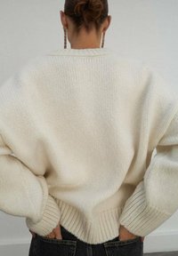 Maglione lavorato a maglia spesso di colore avorio, con orlo e polsini a costine. Il design presenta una vestibilità ampia con spalle scese.