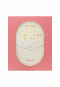 Bracelet en argent avec un motif floral au centre, sur un emballage rose. Le texte lit : "Doublez l'éclat, doublez l'amour."