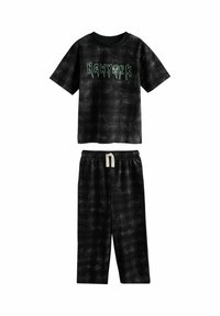 Fekete rövidujjú póló zöld "NEWYORK" grafikával, fekete mintás nadrággal párosítva, mely rugalmas derékkal rendelkezik.