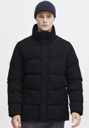 Chaqueta de plumas negra con un alto cuello, que presenta secciones acolchadas y un zipper frontal. La textura parece lisa y acolchada.