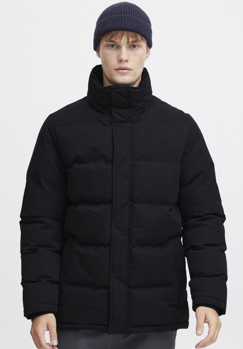 Black puffer jacket with a high collar, featuring quilted sections and a front zipper. Texture appears smooth and padded.
