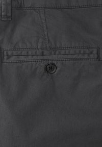Shorts en tissu gris avec une seule poche arrière dotée d'une fermeture à bouton noir. Le matériau semble lisse avec un léger éclat.