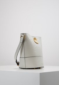 Borsa a secchiello in pelle grigia con stampa coccodrillo, hardware tono oro, design elegante, tracolla regolabile e superficie testurizzata.