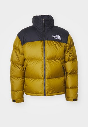 Padded jacket w kolorze musztardowym z czarną nylonową górną częścią, wysokim kołnierzem, suwak z przodu i kieszeniami bocznymi. Na kurtce znajduje się logo The North Face.