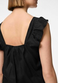 Top senza maniche nero con spalline arricciate e design della schiena arricciato, realizzato in tessuto leggero. Silhouette semplice e moderna.
