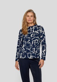 Dunkelblaues Langarmshirt mit einem weißen abstrakten Muster, Rundhalsausschnitt, strukturiertem Stoff und lässiger Passform, kombiniert mit dunklen Hosen.