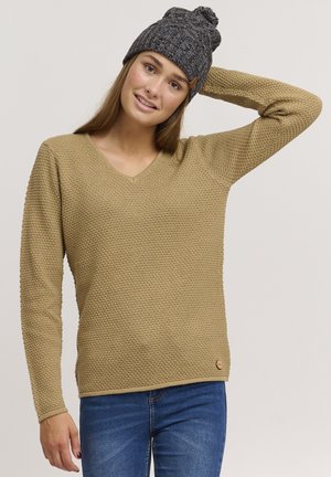 Bež kootud sviiter V-kaelusega ja tekstuuriga mustriga, koos halli kootud beanie mütsiga, millel on peal pom-pom.
