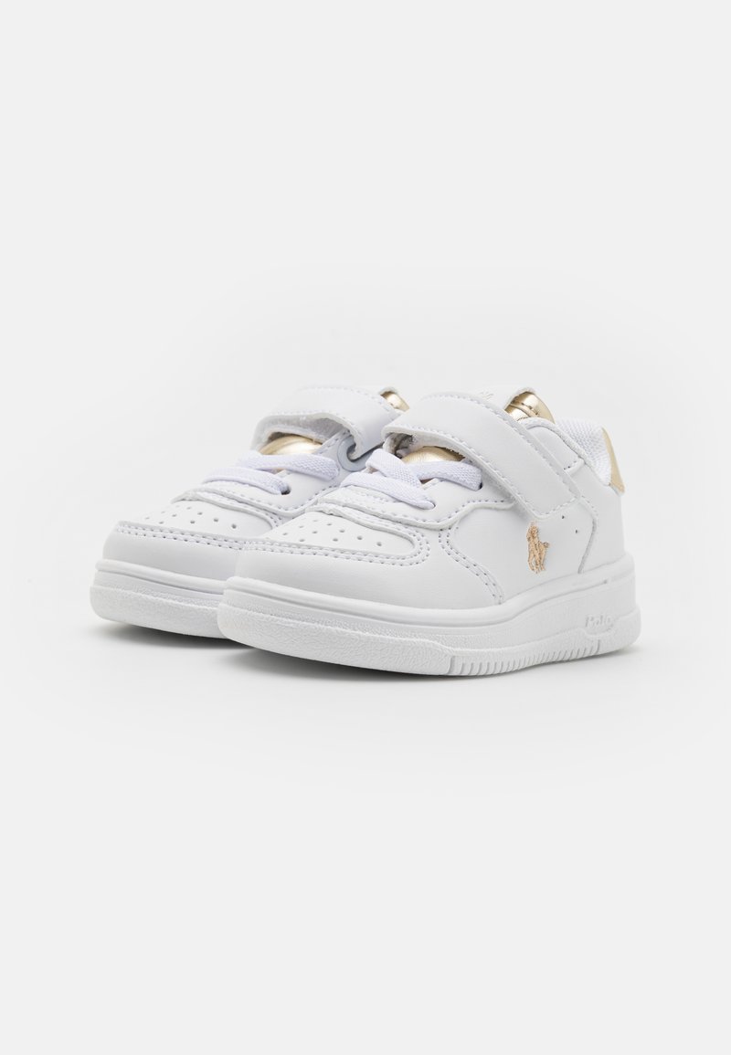 Baskets blanches en cuir avec une semelle texturée, des accents dorés sur la sangle et des perforations sur l'orteil pour une meilleure respirabilité.