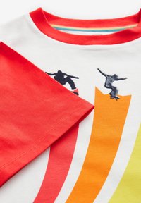 Kortärmad t-shirt med vit kropp och röd krage. Har svarta skateboarder-grafik på färgglada snedställda ränder i orange och grönt.