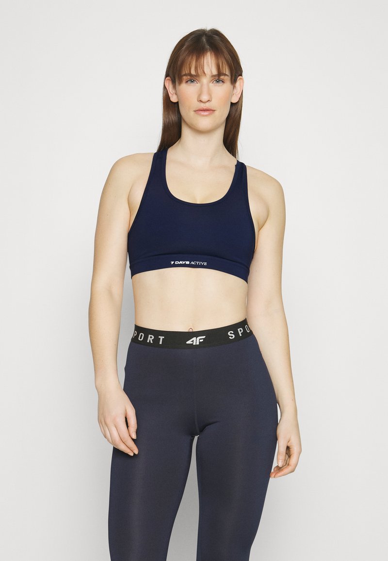 Navy sports bra with a scoop neckline, featuring a logo band. High-waisted navy leggings with a contrasting black waistband marked "SPORT."