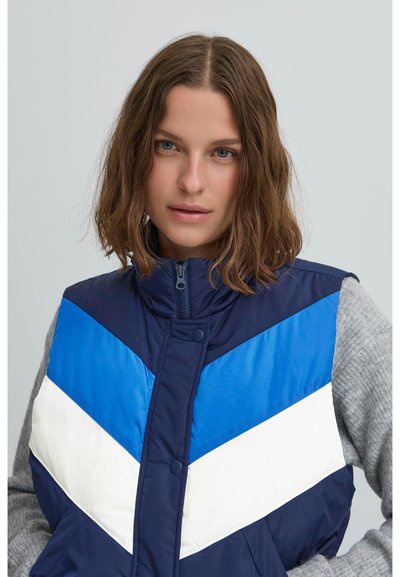 Farbenblockierte Weste in Marineblau, Hellblau und Weiß; mit hohem Kragen, Reißverschluss und Zickzackmuster vorne.