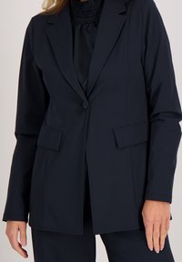 Marineblazer van gladde stof, met notch revers, een enkele knoopsluiting en voorkruiszakken. Eenvoudig en strak ontwerp.