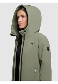 Giacca verde con cappuccio e finitura testurizzata, dotata di chiusura a zip, tasche laterali e un piccolo logo sul petto.