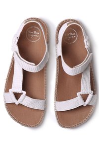 White sandals made of textured leather with adjustable straps, a flat sole, and stitching detail along the edges. Smooth inner lining.
