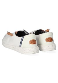 Baskets à enfiler en toile blanche avec des accents en cuir beige, semelles en caoutchouc mouchetées et détails à motif bleu sur le talon.