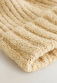 Textil tricotat bej cu un model în dungi, având o textură moale și pufoasă și o margine pliată, creând un aspect cald și confortabil.