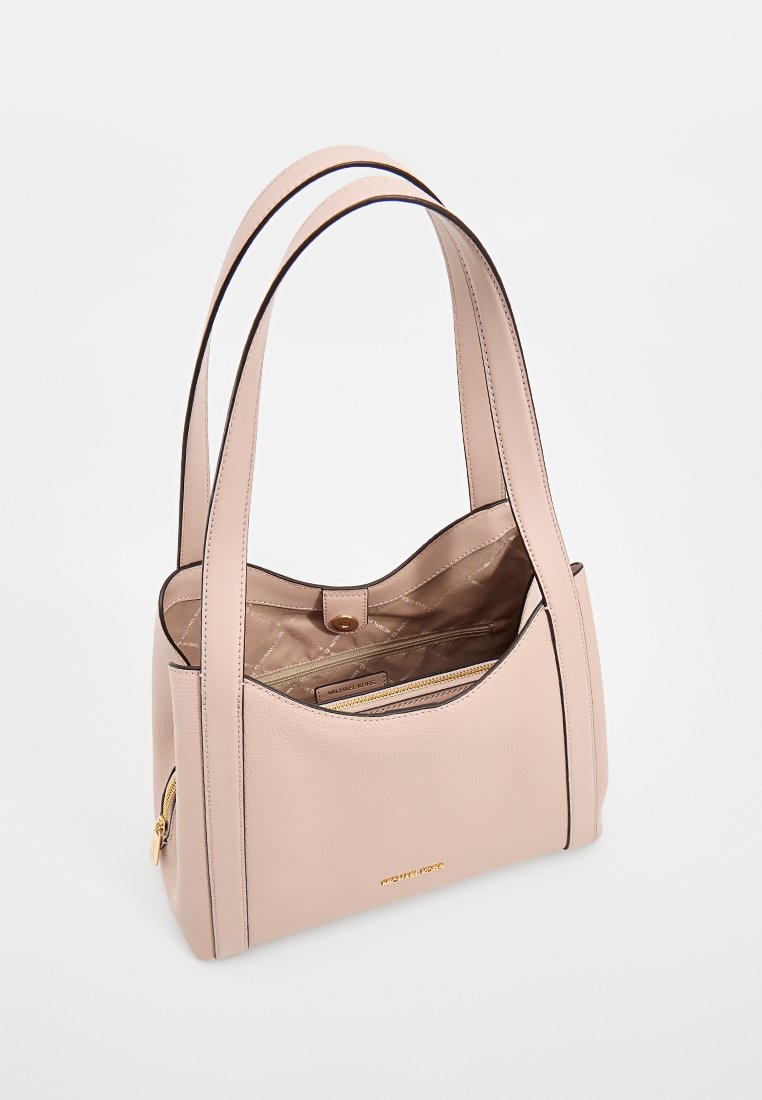 Perzikkleurige leren tote bag met dubbele handvatten, een gladde textuur en contrasterende zwarte details; heeft een ritsvak aan de binnenkant en gouden hardware.