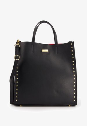 Schwarze Leder-Tote mit goldenen Nieten auf einer Seite, Obergriff, abnehmbarer Schulterriemen und rotem Innenfutter. Goldenes Logo-Detail auf der Vorderseite.