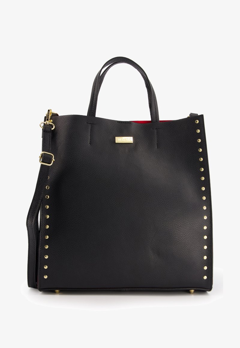 Black leather tote bag with gold studs on one side, top handle, detachable strap, and red interior. Gold logo accent on front.