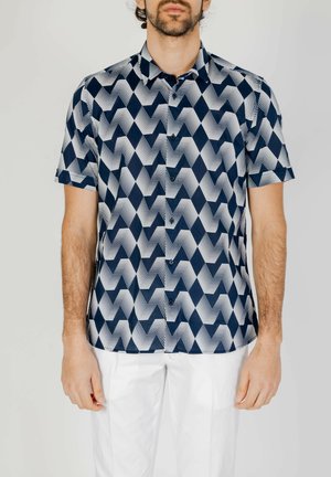 Camicetta a maniche corte con un motivo zigzag geometrico in blu navy e bianco. Presenta una chiusura a bottoni sul davanti e una vestibilità rilassata.