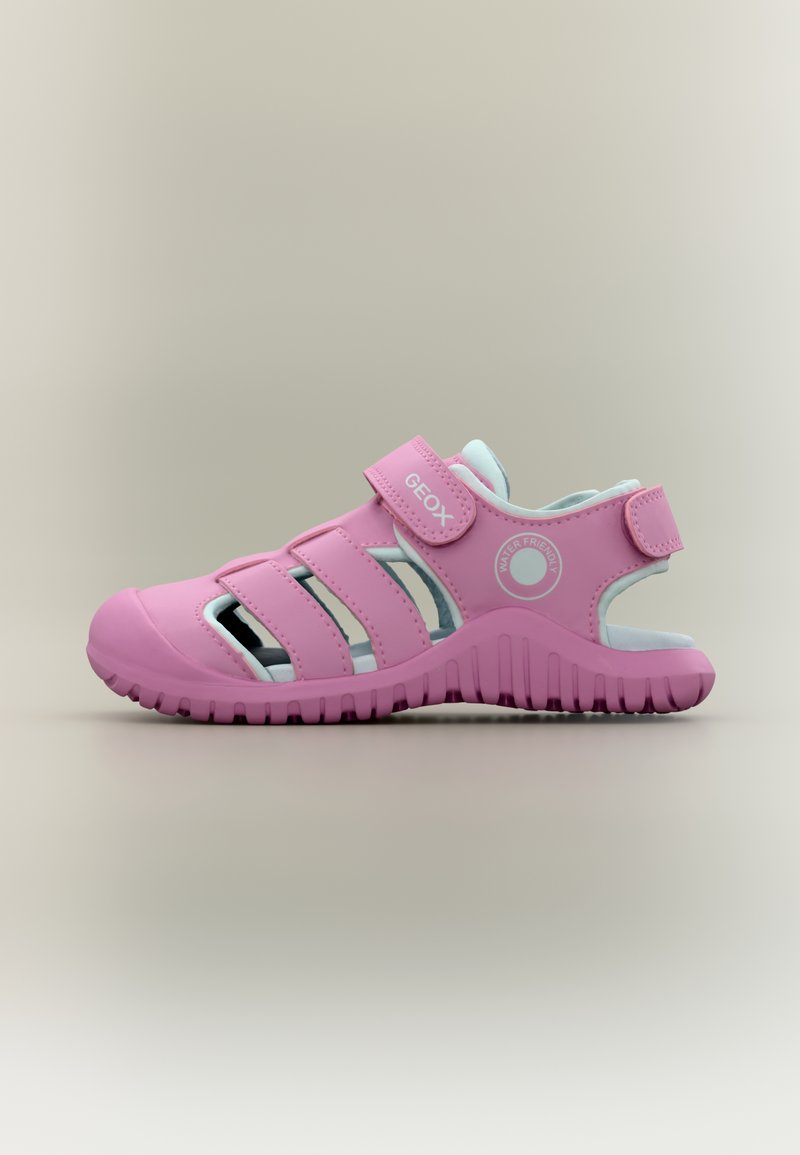 Ροζ παιδικό σανδάλι κλειστού τύπου με ρυθμιζόμενους ιμάντες, λαστιχένια σόλα και ετικέτα «φιλικό προς το νερό» σε ουδέτερο φόντο.