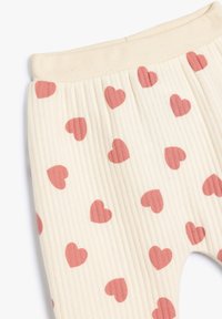 Helle, gerippte Leggings mit einem Muster aus kleinen, rosa Herzen. Weicher, elastischer Bund mit einer glatten Textur.