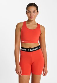 Rotes sportliches Crop-Top und Shorts-Set aus elastischem Stoff. Das Top verfügt über einen runden Ausschnitt; die Shorts haben einen schwarzen elastischen Bund mit Logo.