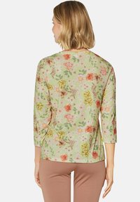 Blumen Langarmtop aus leicht grünem Stoff, mit mehrfarbigen Mustern von Rosen, Lilien und Blättern. Weicher Stoff mit rundem Halsausschnitt.