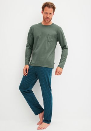 Groen topje met lange mouwen en een borstzakje, gecombineerd met teal pyjamabroek met een klein wit polkadotpatroon.