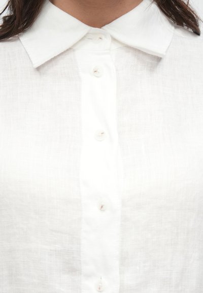 Λευκό πουκάμισο από λινό με κουμπιά μπροστά, κλασικό γιακά και εμφανές υφή ύφασμα. Απαλό, διαπνέον υλικό με διακριτική γυαλάδα.