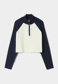 Crop top med hög krage och fjärdedels dragkedja. Ribbad textur i marinblå och krämfärgad, med kontrasterande färgblockdesign på ärmarna.