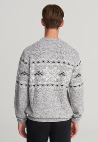 Maglione grigio a maglia con un motivo a fiocco di neve bianco e nero sulla parte posteriore. Maniche lunghe con polsini e orlo a costine. Scollatura rotonda.