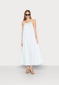 Vestido maxi azul claro com decote franzido, alças finas nos ombros e design em camadas. Usado com sandálias marrons com tiras e óculos de sol.