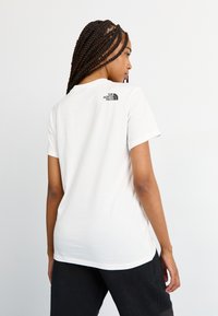 Tricou alb cu mânecă scurtă și guler rotund, având un logo negru pe spate. Material moale din bumbac, croială lejeră și design minim.