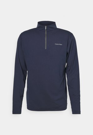 Pullover de mangas longas em navy em tecido suave, apresenta um fecho de zíper de um quarto e um pequeno logo branco na área do peito esquerdo. Ajuste clássico.
